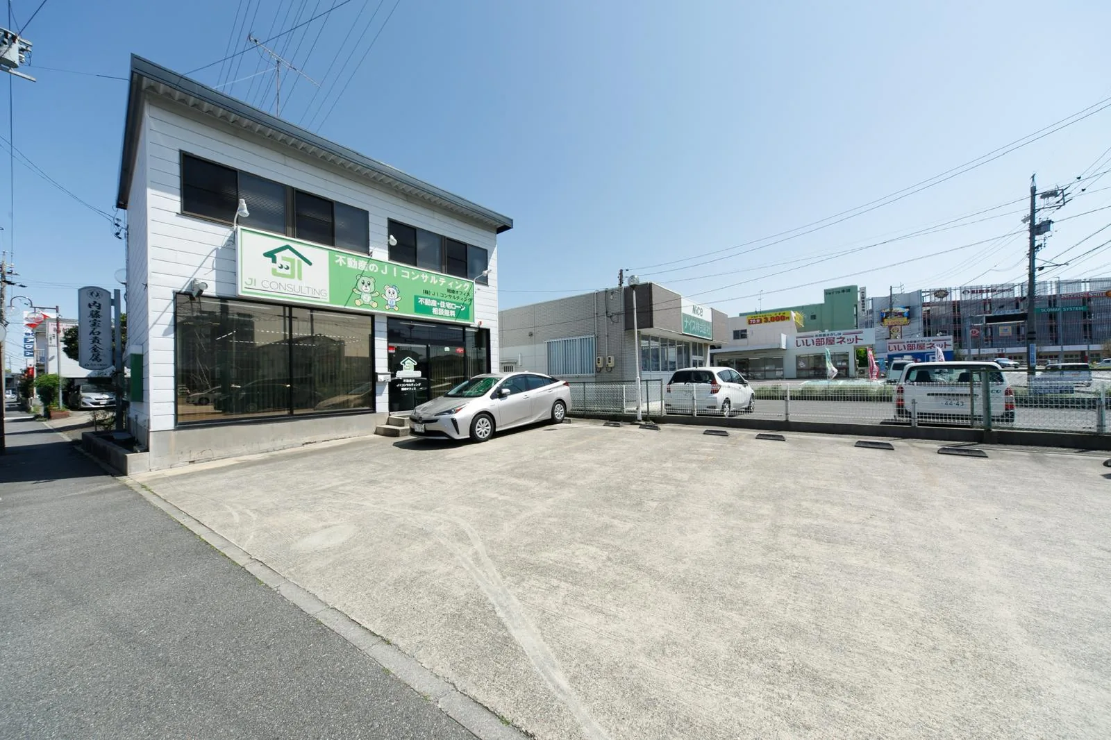 Fachada da loja da Ji Consulting em Okazaki, com placa verde e estacionamento próprio